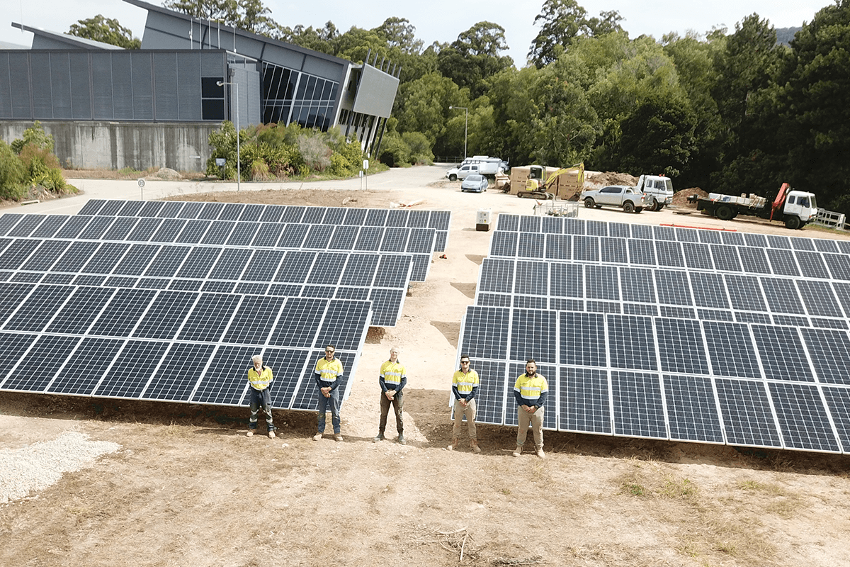4 men in high vis standing in front of solar panels 