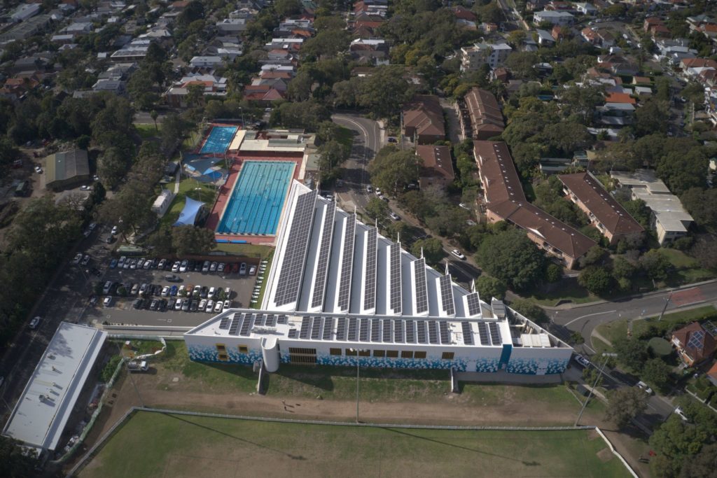 Drone image of Manly Aquatic Centre, showing rows of solar panels installed on the roof